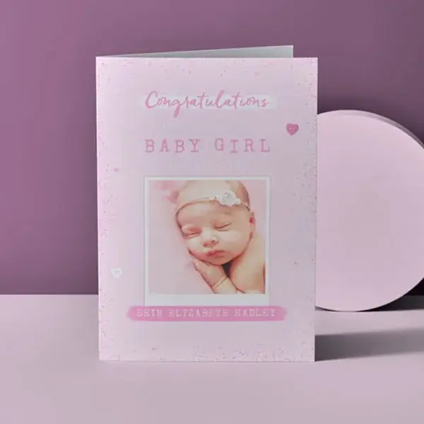Personalised baby girl congratulations card featuring a newborn photo, soft pink design, and custom name detail on a pastel lilac background.